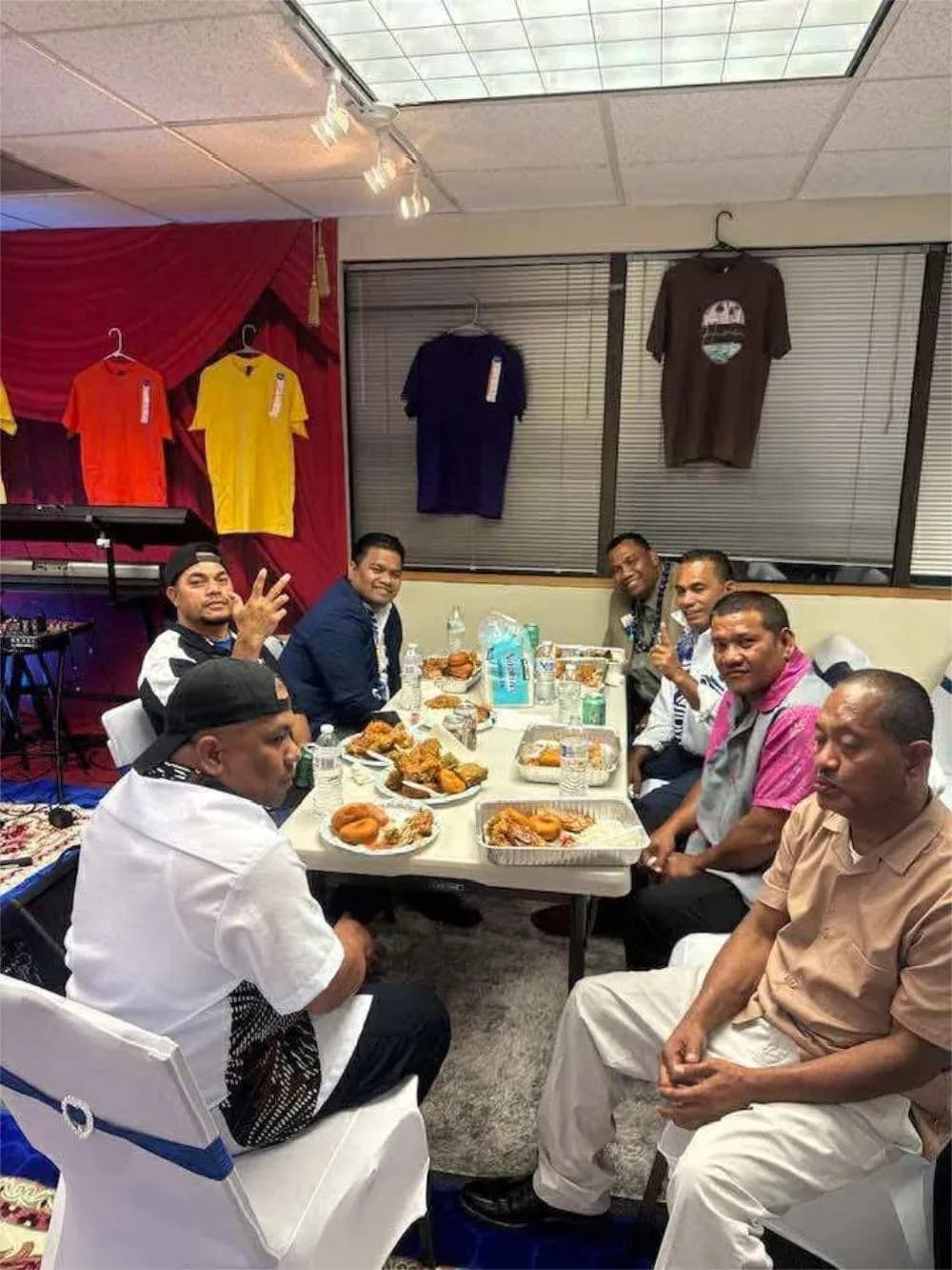Men of the church sitting around a table together over a shared meal, talking and laughing.