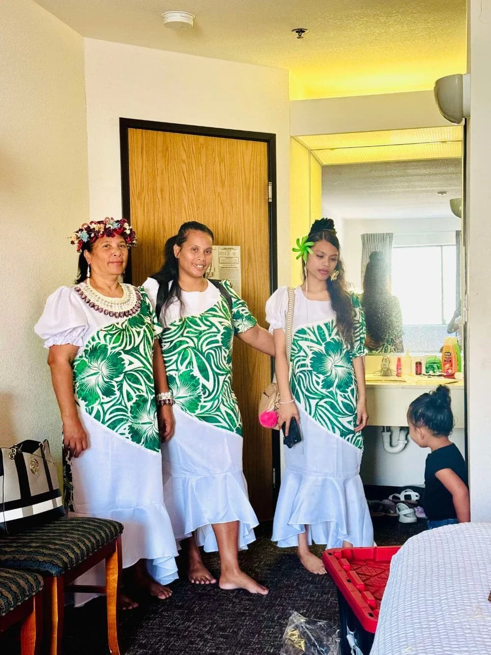 Three women in matching green and white island dresses before a church program.