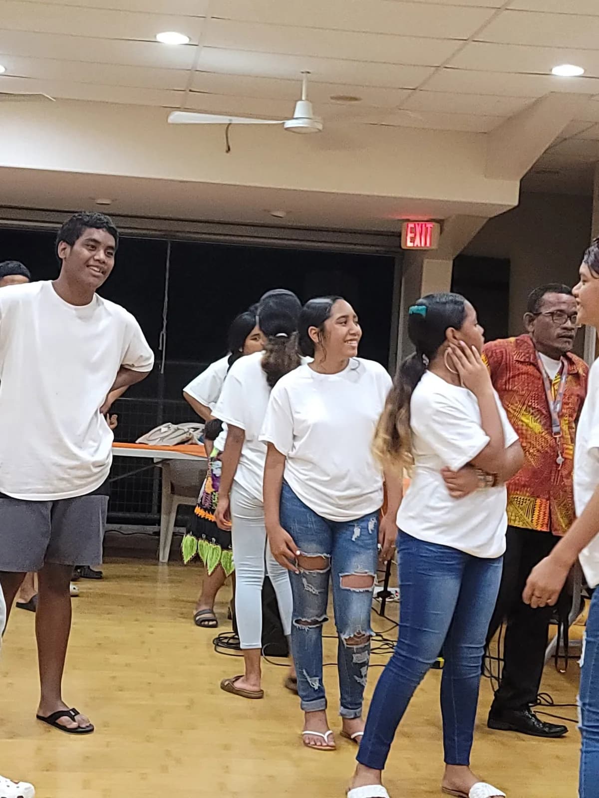 Teenagers from the youth group standing together in matching white shirts before a service.